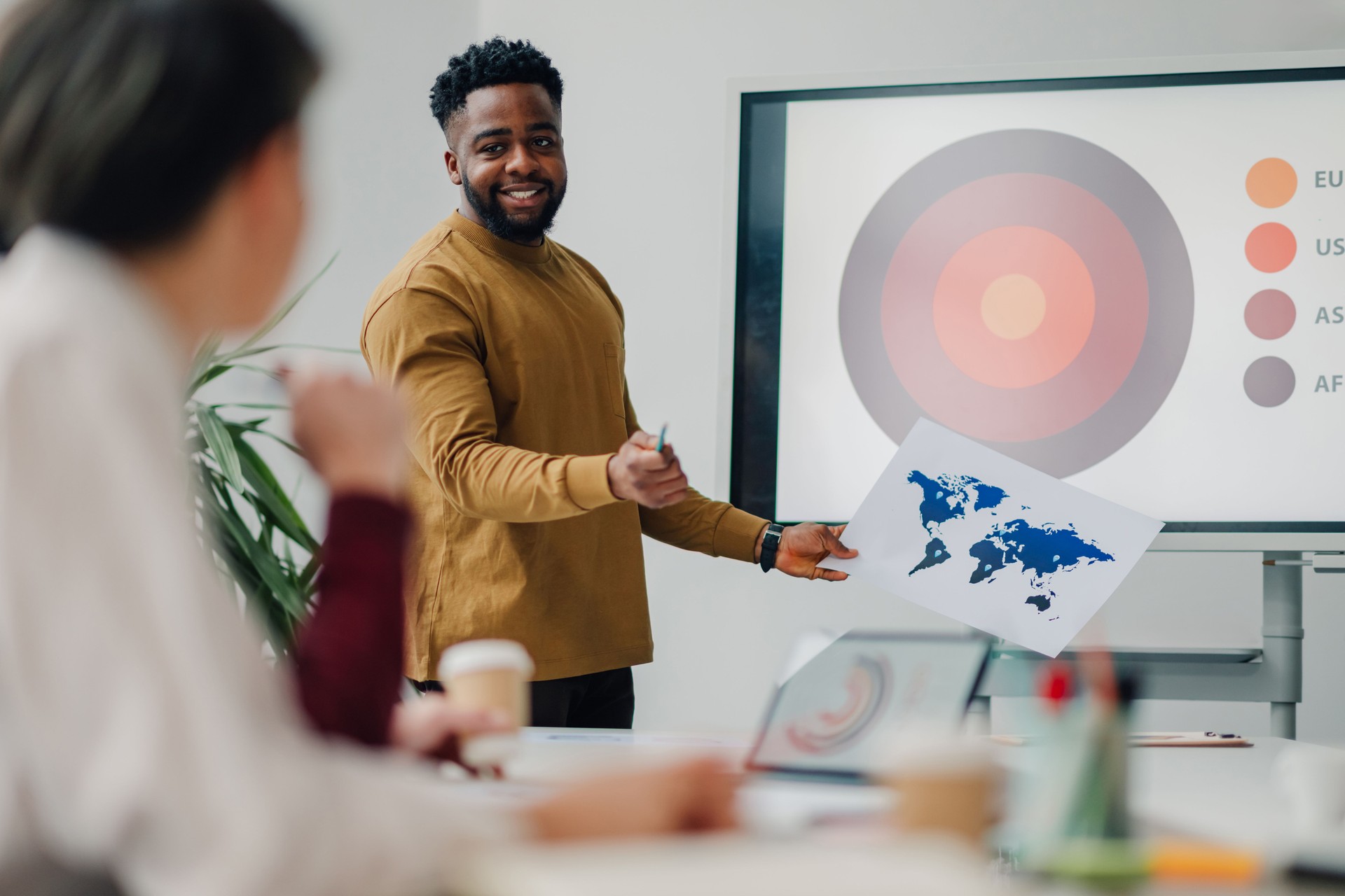 Young businessman holding world map explaining global marketing strategy during a meeting